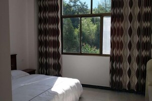 A bedroom with a bed, a window, and curtains.