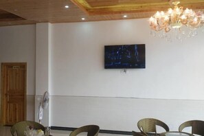 A room with a television mounted on the wall, wicker chairs, a chandelier, and a wooden door. - Grand Canyon View Inn (Enshi City)