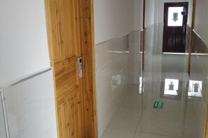 A hallway with a wooden door, a glass wall, and a green directional sign on the floor. - Grand Canyon View Inn (Enshi City)