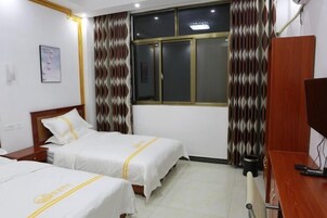 Habitación de hotel con dos camas, un escritorio, una silla, un televisor y una ventana con cortinas.
