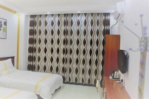 Habitación de hotel con dos camas, una mesita de noche de madera, un televisor y un equipo de aire acondicionado instalado en la pared.