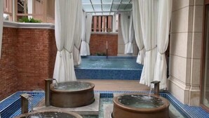 Un área de spa con una piscina pequeña, dos jacuzzis y una pared de ladrillo.