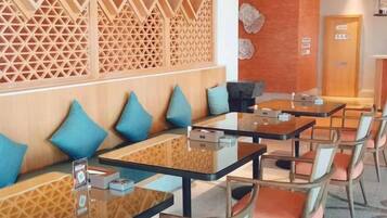 A restaurant with wooden partitions, cushioned seating, and tables with chairs.
