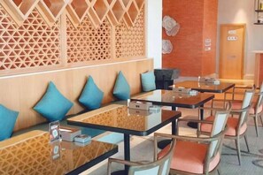 A restaurant with wooden partitions, cushioned seating, and tables with chairs. - Qianshen Hotel (Suzhou)