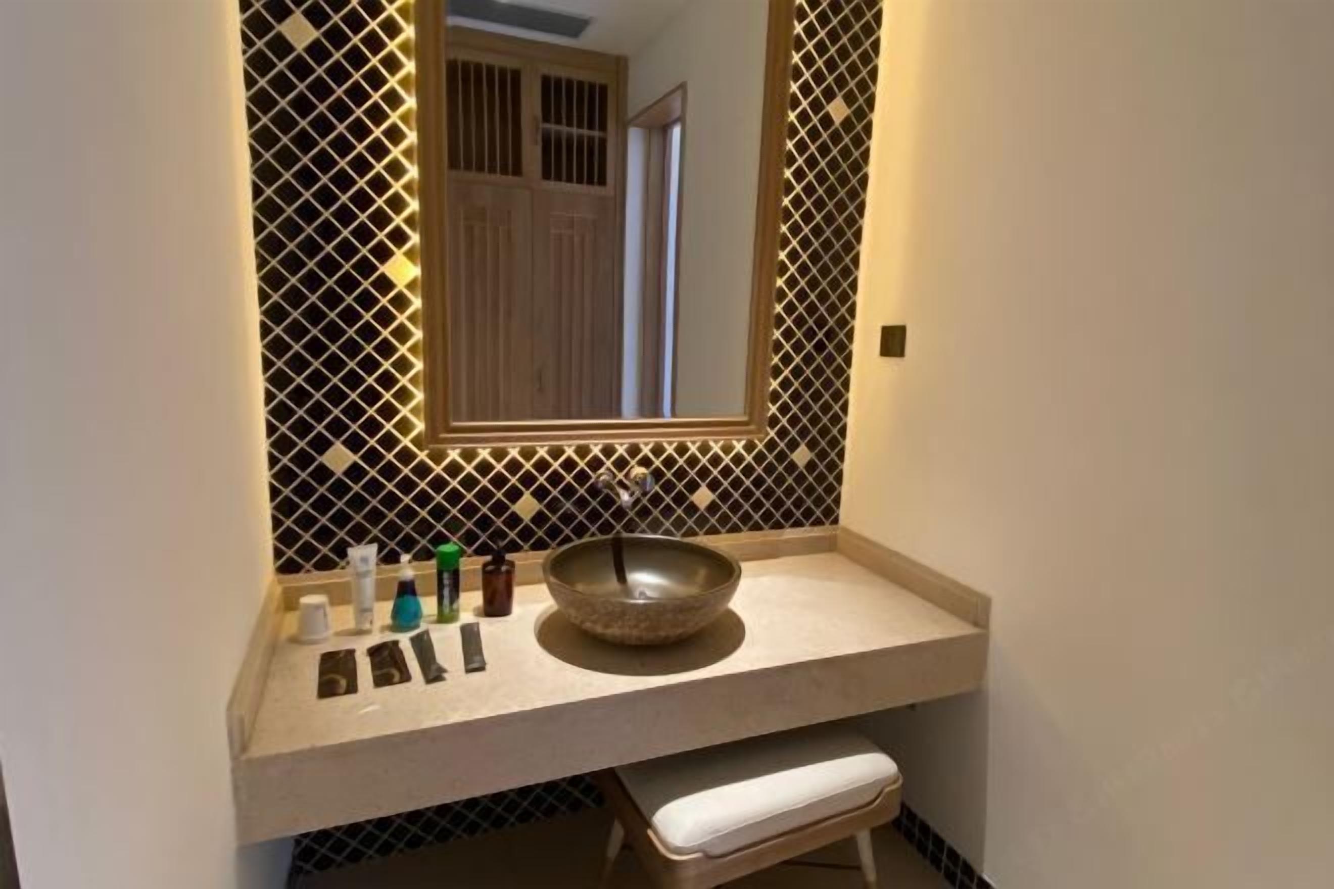 Un baño con un lavabo color beige, un espejo y un toallero.