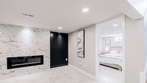Un dormitorio con cama, un armario negro, pared con diseño de mármol y un cuadro enmarcado.