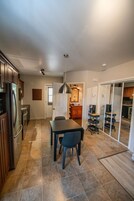 Una cocina moderna con armarios oscuros, un refrigerador de acero inoxidable y un comedor con mesa y sillas.
