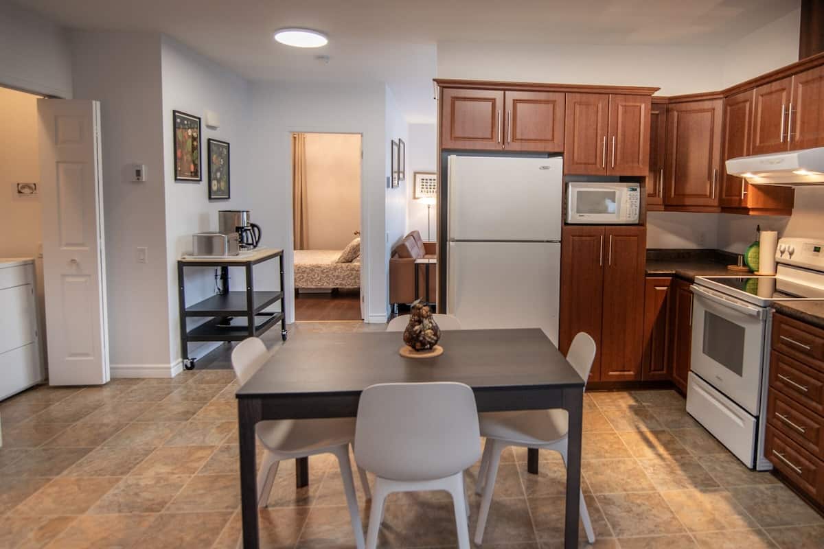 A compact kitchen with a refrigerator, microwave, oven, and wooden cabinets.