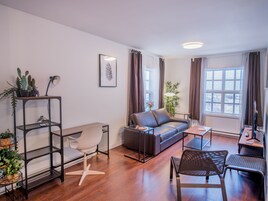 Una sala de estar moderna con un sofá, una mesa de centro y sillas, un escritorio pequeño y una estantería para plantas.