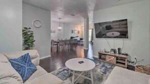 A spacious living room with a large TV, a dining area, and a kitchen in the background. - Beckley's place (Jacksonville)