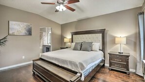 A bedroom with a large bed, a ceiling fan, a nightstand, and a lamp. - Beckley's place (Jacksonville)