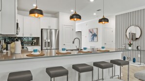 A modern kitchen with white cabinets, stainless steel appliances, and a central island with bar stools.