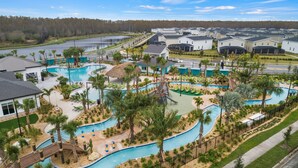 A resort with multiple swimming pools, palm trees, and a lake in the background.