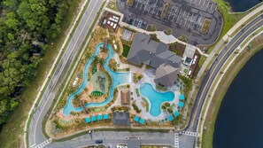 Eine Luftaufnahme eines Resorts mit mehreren Schwimmbecken, einem Parkplatz und einer Straße.