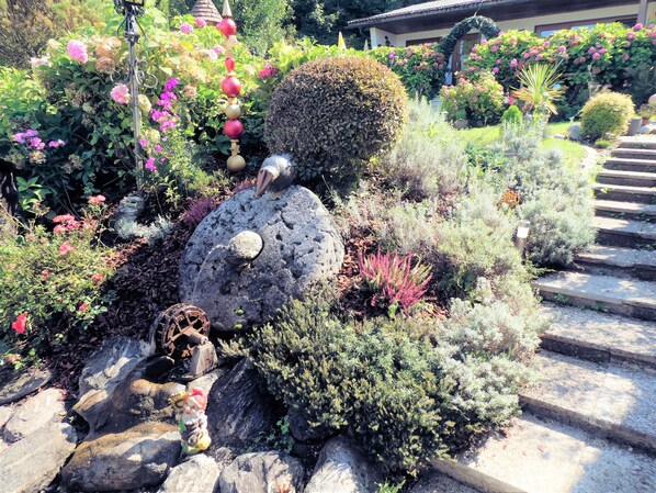 Stroll through the beautifully landscaped garden, featuring vibrant hydrangeas and a decorative stone sculpture.