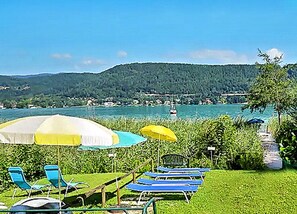 Relax in a serene lakeside setting with comfortable lounge chairs and a shaded area.