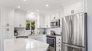 Una cocina moderna con armarios blancos, electrodomésticos de acero inoxidable y una isla grande.