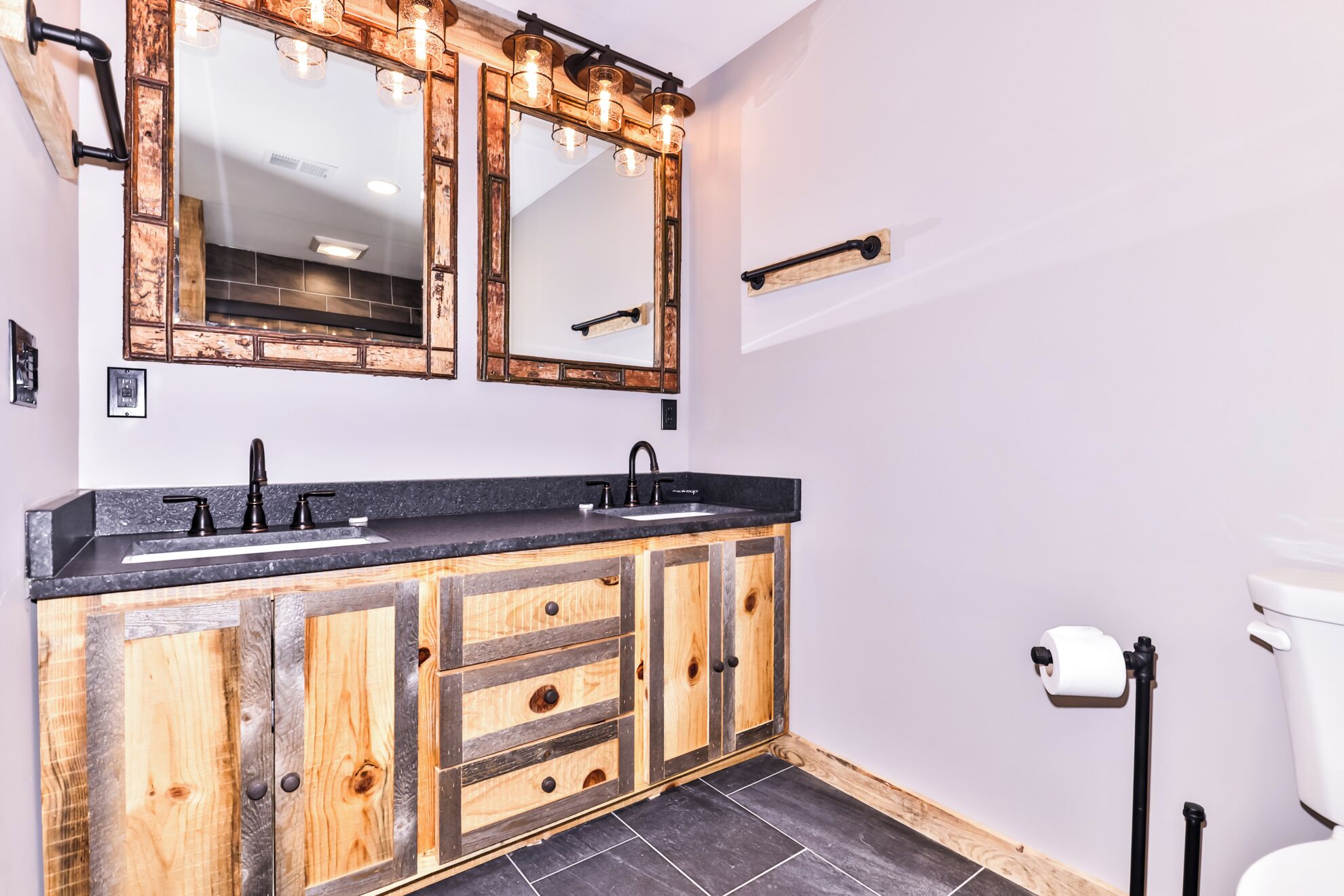 A bathroom with a wooden vanity, a large mirror, and a toilet.