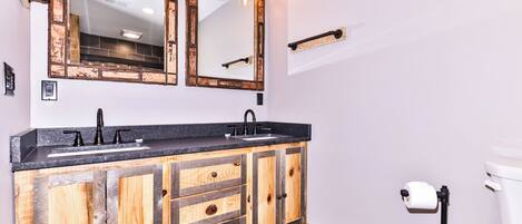 A bathroom with a wooden vanity, a large mirror, and a toilet.