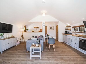 Ein kompakter Wohnraum mit Küchenzeile, Essbereich und Sitzecke mit Sofa und kleinem Tisch.