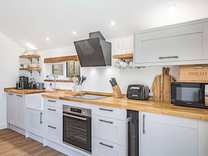 A modern kitchen with white cabinetry, a built-in oven, a microwave, and a bread box.