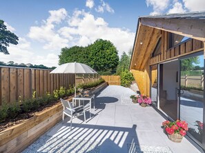 A patio with a table and chairs, a wooden fence, and a building with a glass door.