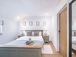 A bedroom with a bed, bedside tables, a wooden wardrobe, and framed pictures on the wall.