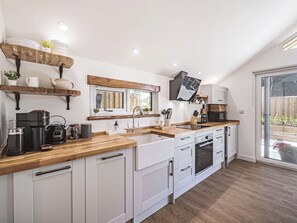 Eine moderne Küche mit weißen Schränken, Holz Arbeitsplatten, einem Einbauofen und einem Fenster mit Blick auf einen Garten.