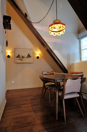 A dining area with a wooden table and chairs, a hanging light fixture, and a framed picture on the wall. - Appartement Jacques-Cartier (Saguenay)