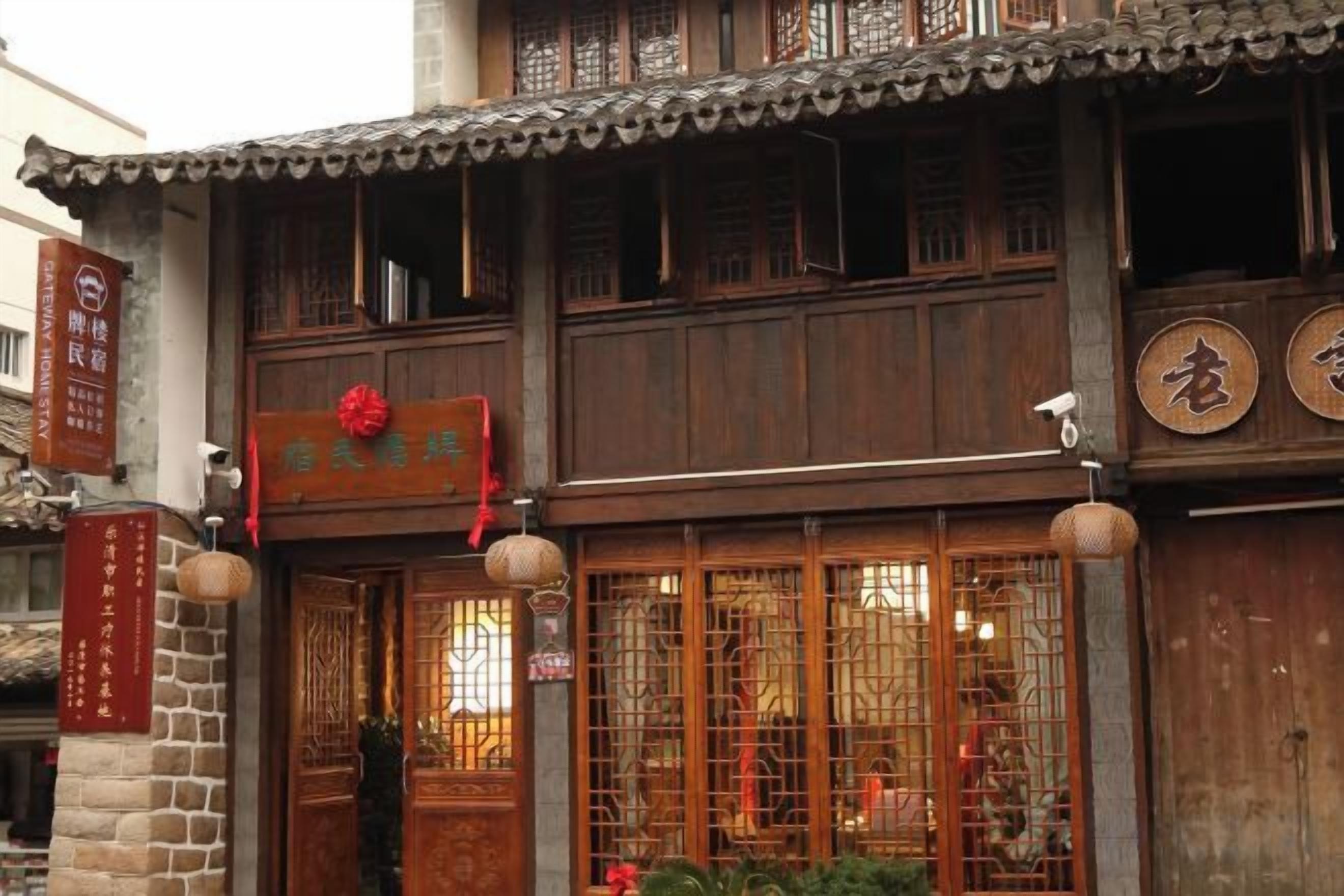 A traditional wooden building with a signboard, a tiled roof, and a decorative lantern.
