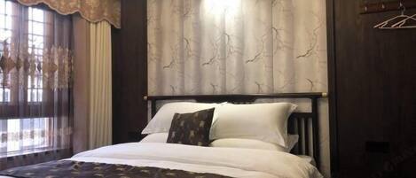 Quarto com cama grande, cabeceira de madeira escura e parede estampada.
