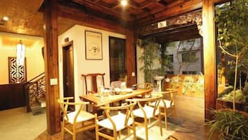 A wooden dining area with a table and chairs, a staircase, and a view of greenery outside.