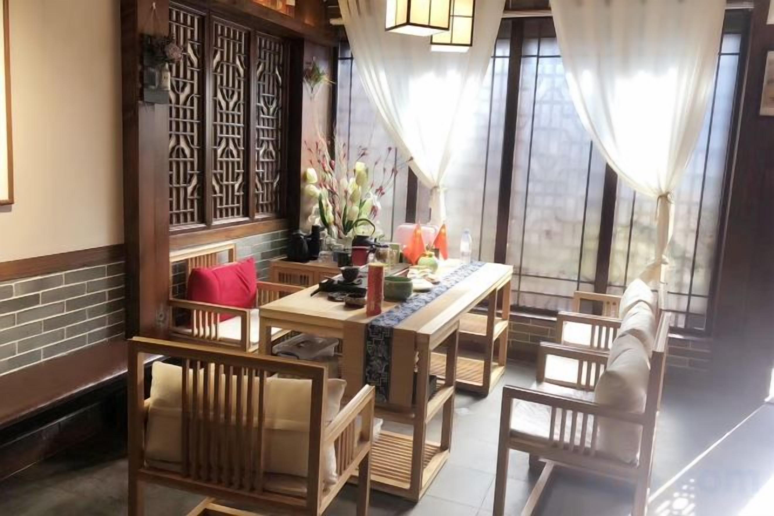A traditional Japanese-style room with tatami flooring, a low wooden table with a red cushion, and a view through a shoji screen.