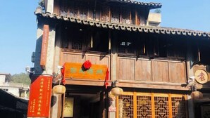 A traditional building with a wooden facade, a signboard, and a decorative gate. - Pailou Guesthouse (Yueqing)