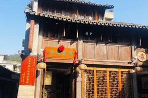 A traditional building with a wooden facade, a signboard, and a decorative gate. - Pailou Guesthouse (Yueqing)