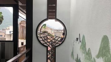 A circular decorative element with a geometric pattern, a view of buildings through a window, and a wall with green abstract designs.
