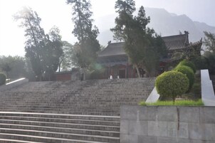 Un edificio tradicional con techo de tejas, rodeado de árboles y una escalera de piedra que conduce hasta él.