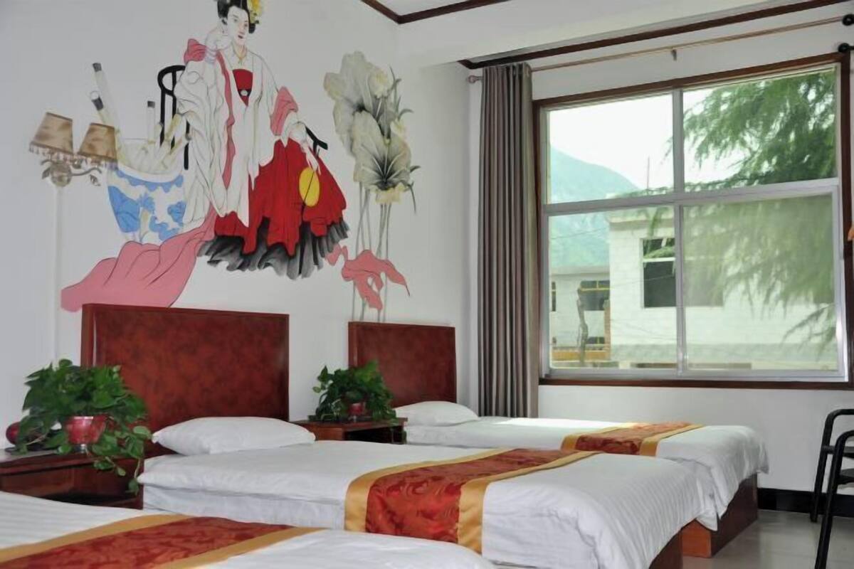 Ein Hotelzimmer mit zwei Betten, einem großen Fenster und einem Wandbild.