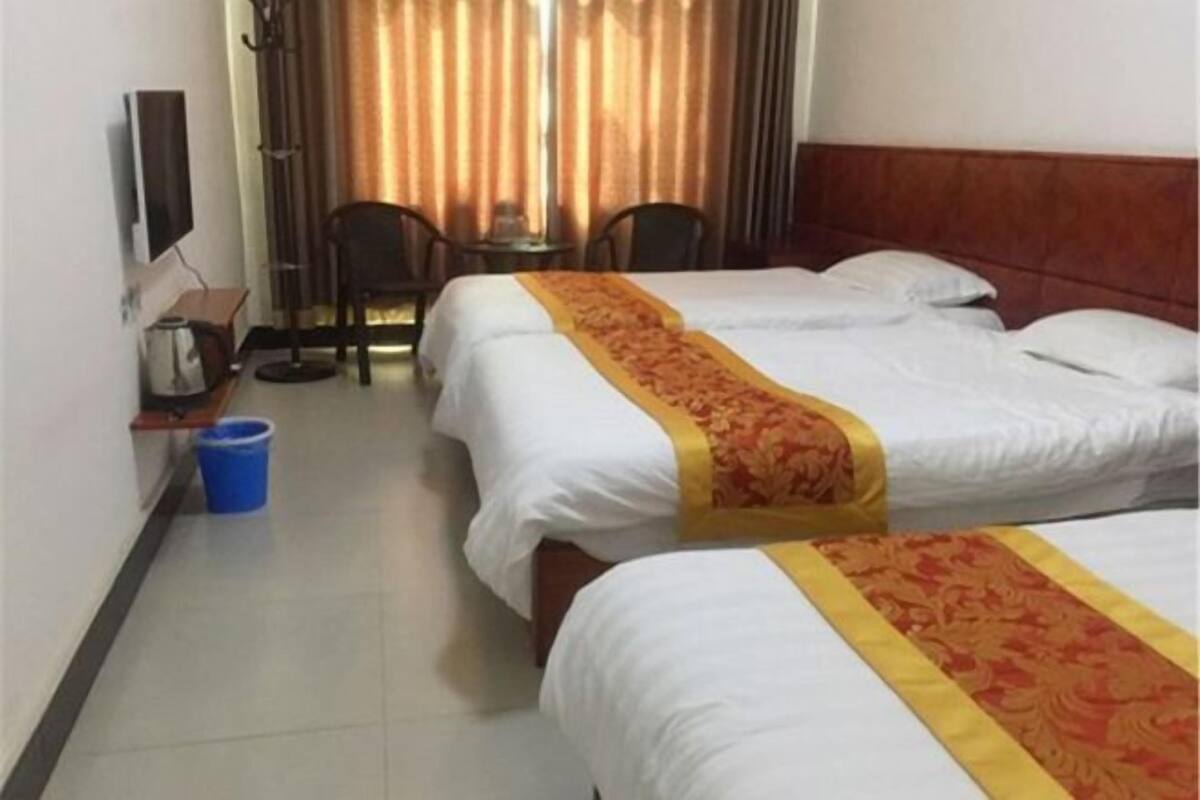 Ein Hotelzimmer mit zwei Betten, einem Fernseher, einem kleinen Tisch und einem Stuhl.