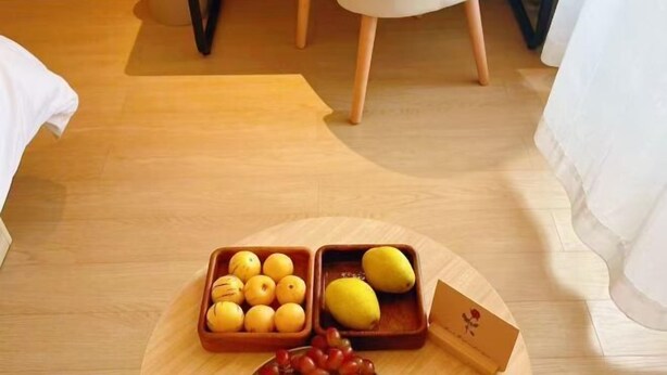 A wooden floor with a round table holding a fruit bowl with lemons and a card. - Homeinn · neo (Liuzhou Five Star Pedestrian Street) (Liuzhou)