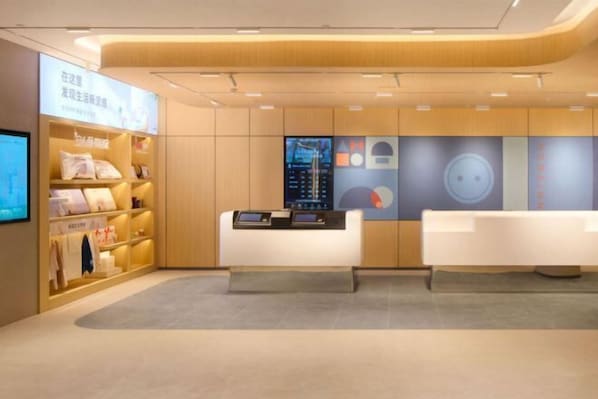 A modern reception area with a wooden reception desk, a digital display, and a seating area. - Homeinn · neo (Liuzhou Five Star Pedestrian Street) (Liuzhou)