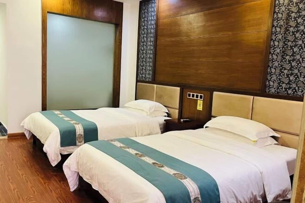 A hotel room with two beds, wooden headboards, and a patterned wallpaper.