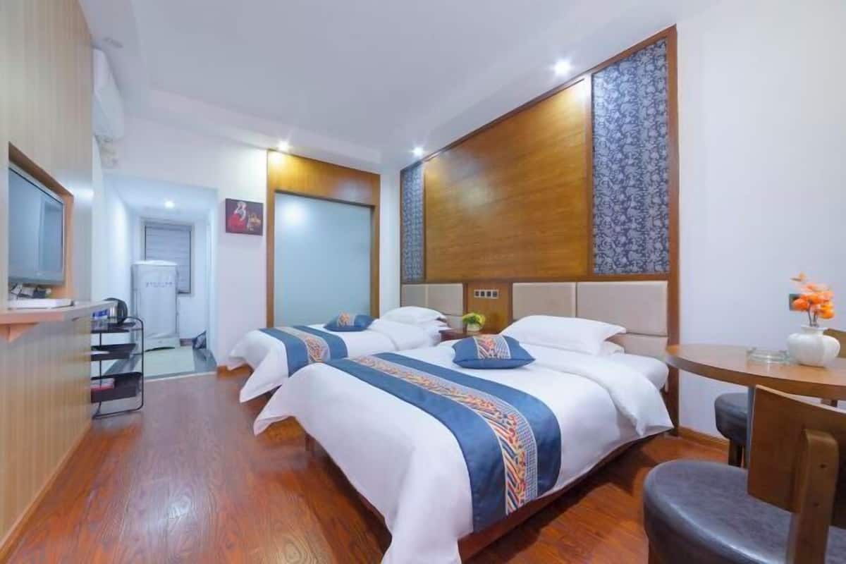 A hotel room with two beds, a wooden headboard, a small table, and a chair.
