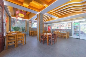 A restaurant interior with wooden tables and chairs, a tiled floor, and a menu display. - Changsha Hotel (Zhangjiajie Wulingyuan Landmark Gate) (Zhangjiajie)