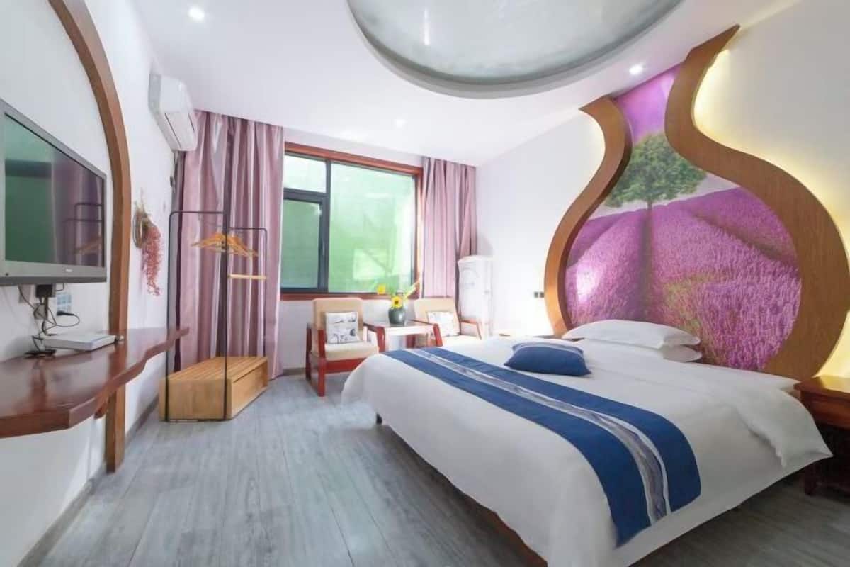 A hotel room with a bed, a desk, a chair, a TV, and a window.