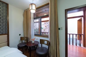 Ein Hotelzimmer mit Bett, Esstisch mit Stühlen, einem Fenster mit Vorhängen und einem Balkon mit Geländer.