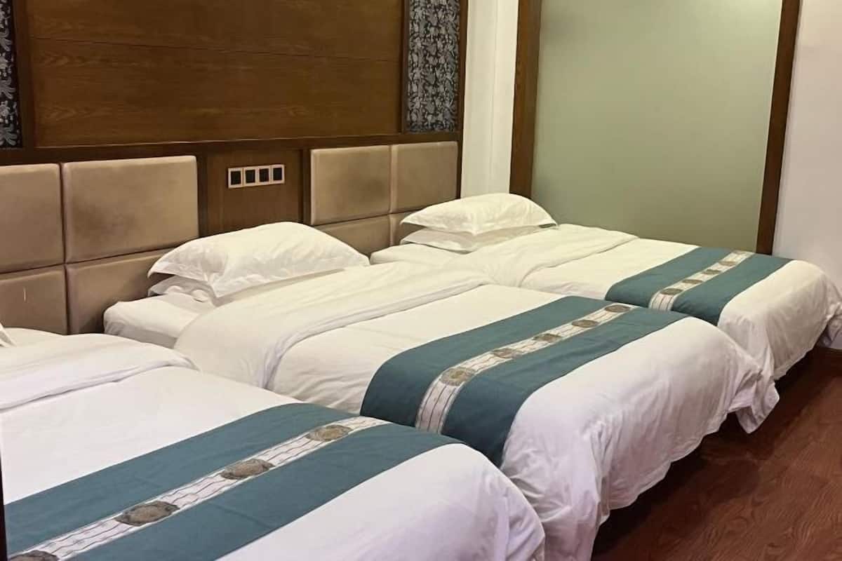 A hotel room with two beds, a wooden headboard, and a light-colored wall.