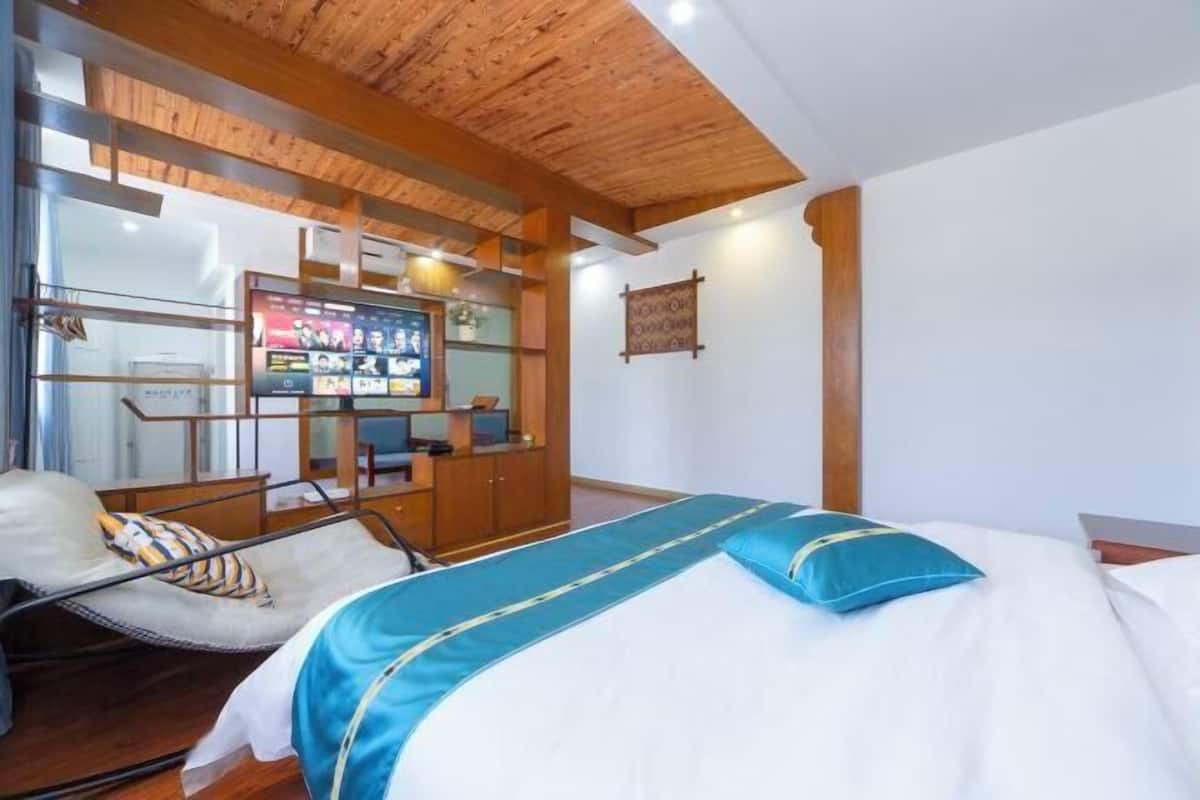 A hotel room with a bed, a chair, a desk with a computer, and a TV.