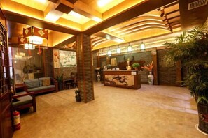 Eine Hotelhalle mit Rezeption, Sitzgelegenheiten und Zierpflanzen.