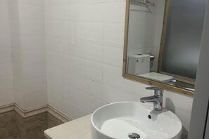 A bathroom with white tiled walls, a white sink with a chrome faucet, and a mirror above the sink. - Changsha Hotel (Zhangjiajie Wulingyuan Landmark Gate) (Zhangjiajie)